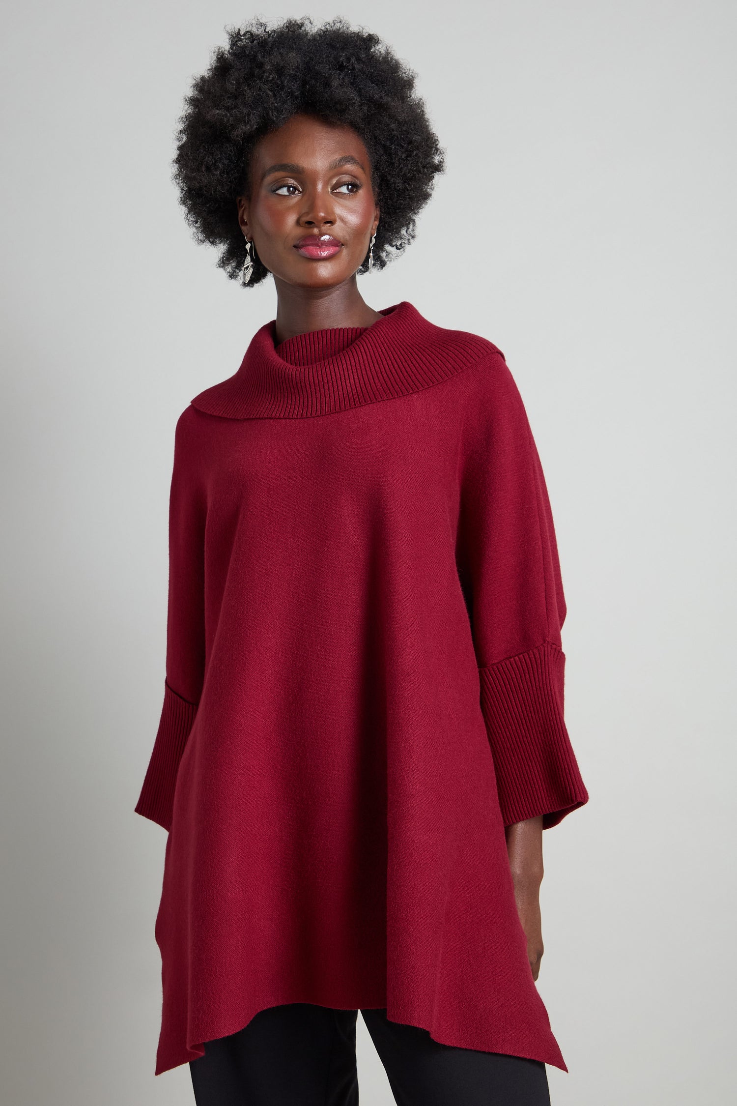 Dressed in a red Roll Neck Knit with long sleeves, the individual poses confidently against a plain background.