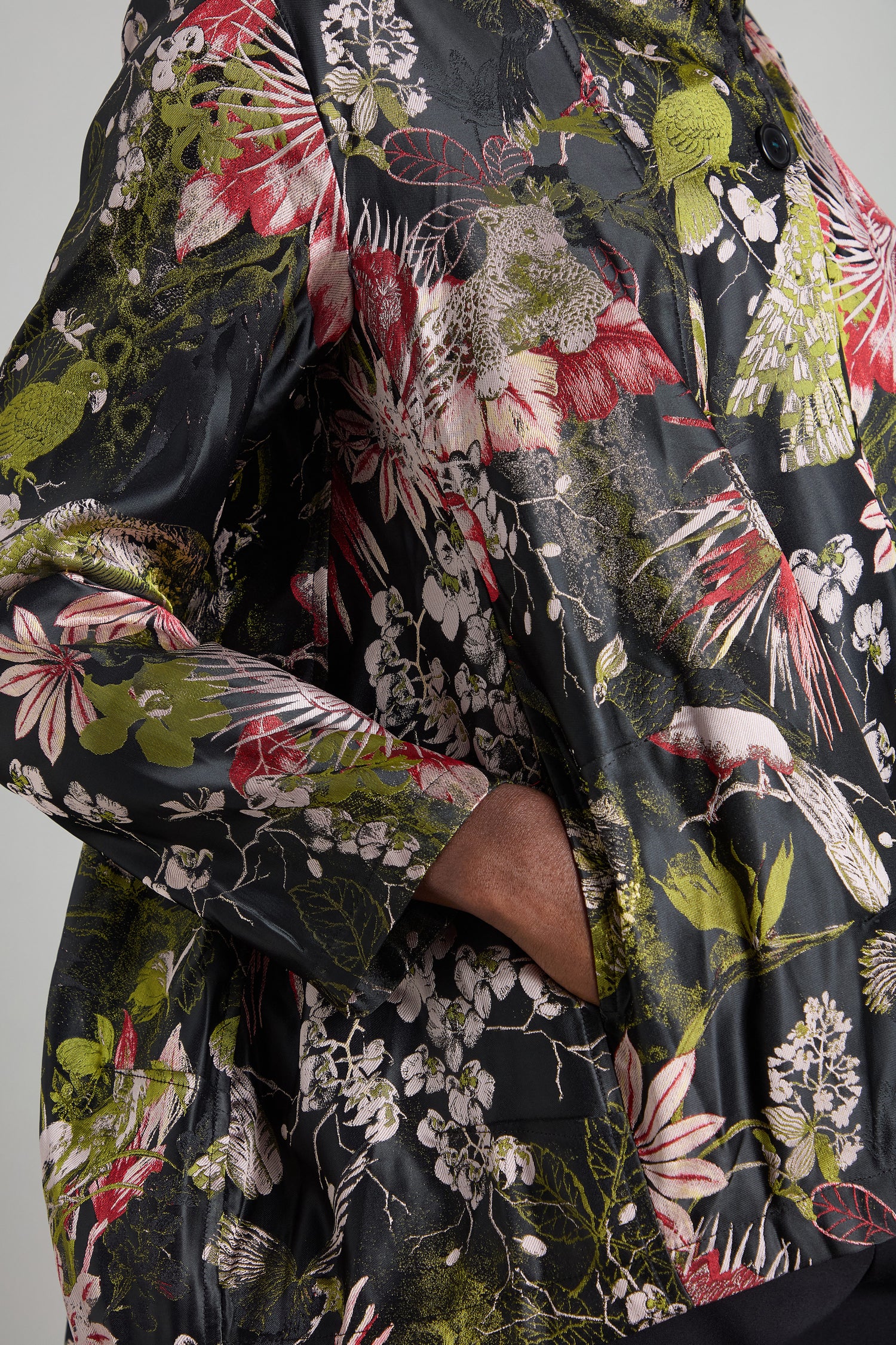 A person wearing the Jacquard Floral Jacket, which evokes the beauty of an Oriental garden, stands with one hand in the pocket.