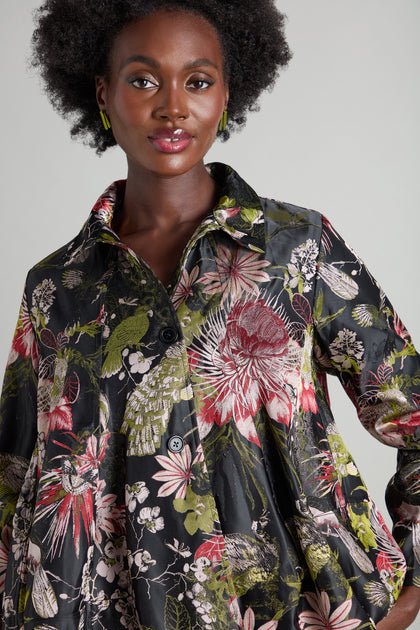 Wearing the Jacquard Floral Jacket, an individual is posed against a simple backdrop, radiating the allure of an oriental garden.