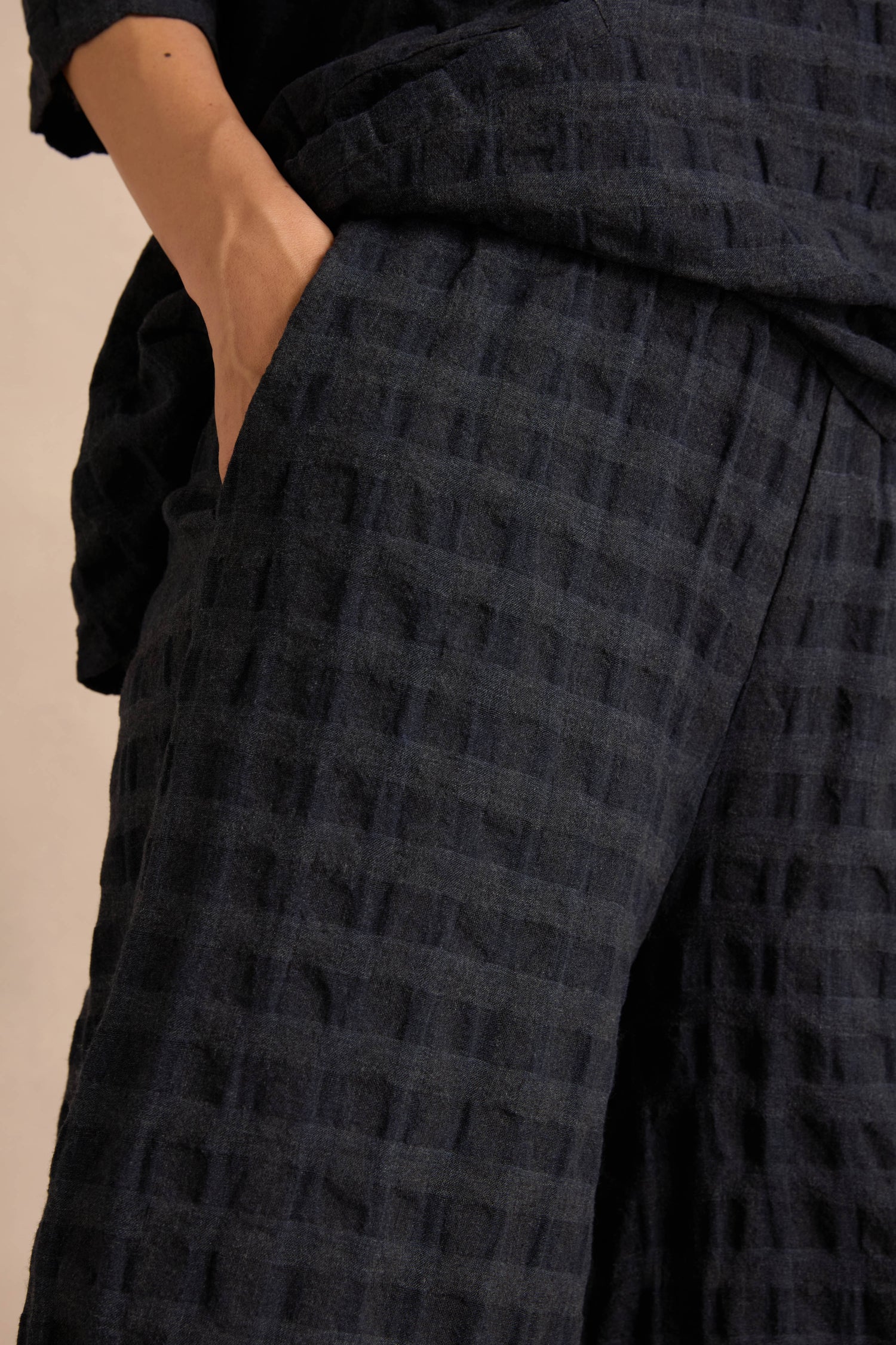 Close-up of a person wearing Navy Waffle Check Wide Trousers and a matching shirt, with one hand placed in the side pocket of the trousers.