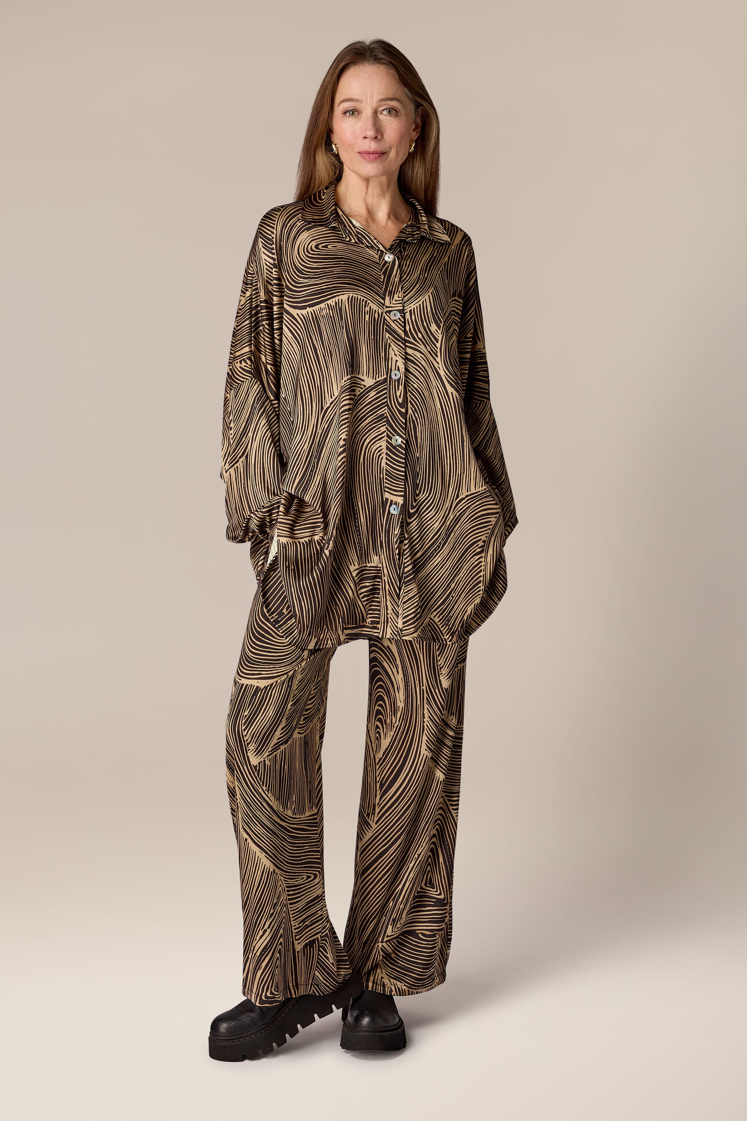 A woman wearing a Swirl Pant, a contemporary design brown pajama set with artisanal flair.