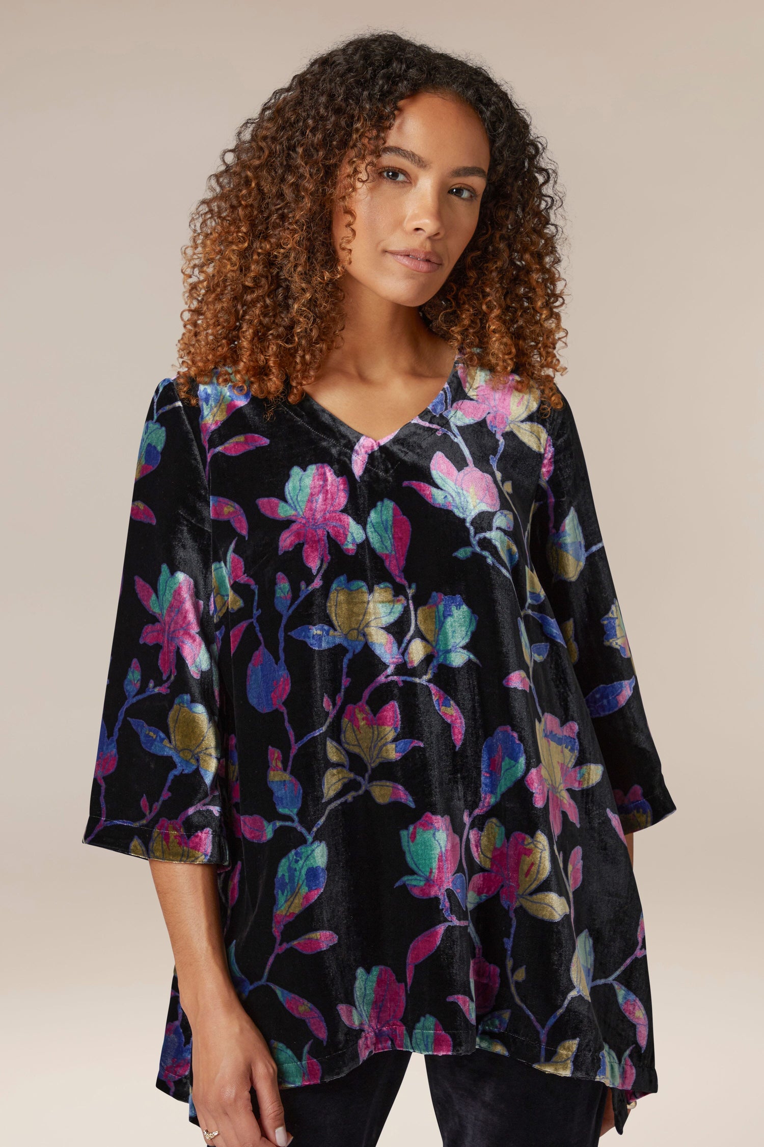 A woman wearing a black velvet Winter Magnolia Velvet Tunic with colorful floral print.