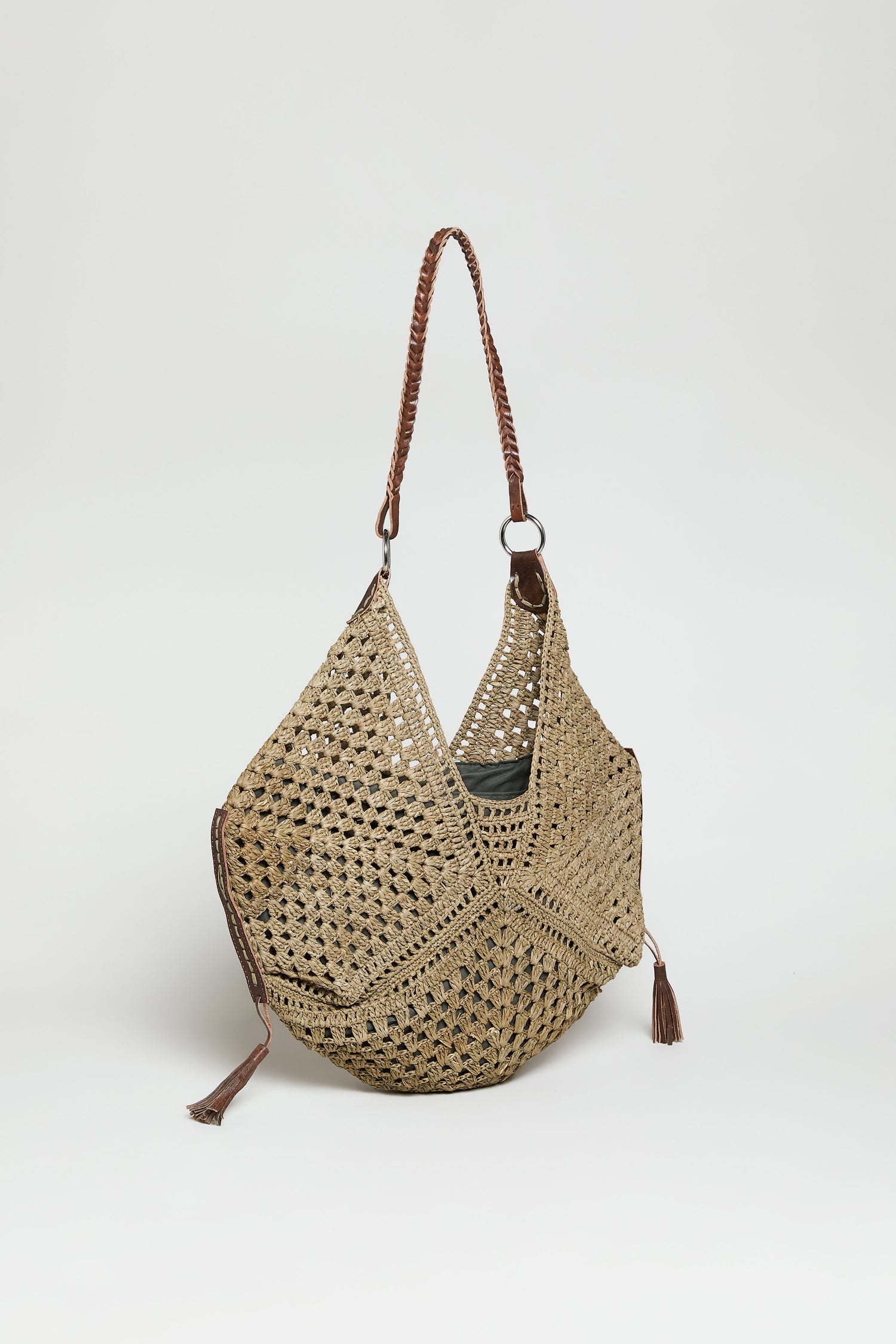 The Handwoven Raffia Tassel Detail Handbag features a tan geometric pattern, braided shoulder strap, and decorative tassels, shown against a plain white background.