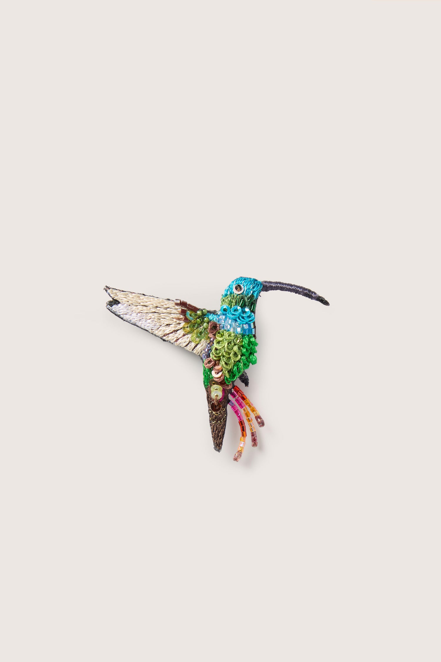 The Hand Embroidered Sequin Hummingbird Brooch features a stunning array of blue, green, and brown hues, intricately detailed with delicate sequins, and is presented against a plain white background.