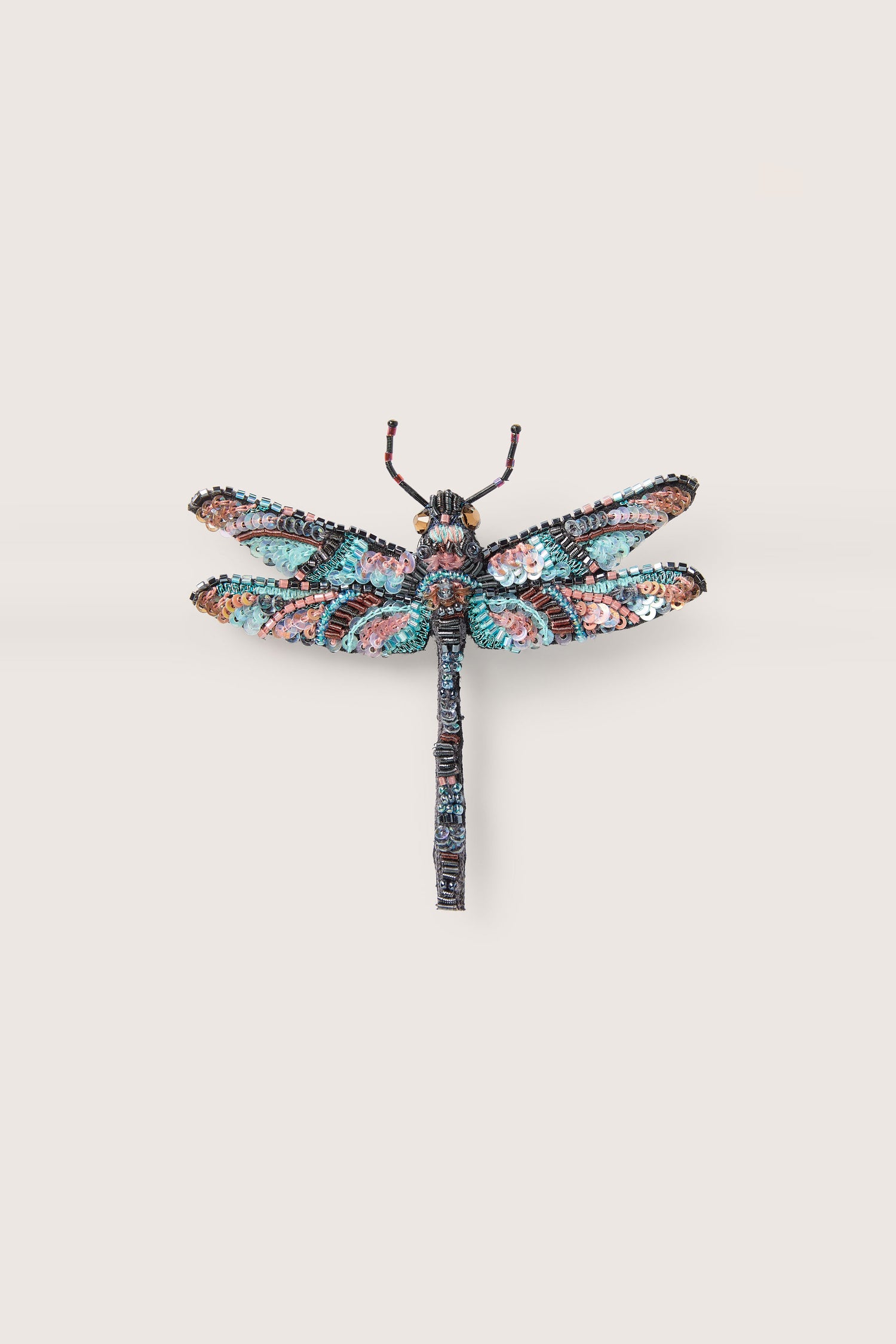 A multicolored, hand beaded sequin dragonfly brooch by Trovelore with intricate detailing is displayed on a neutral background.