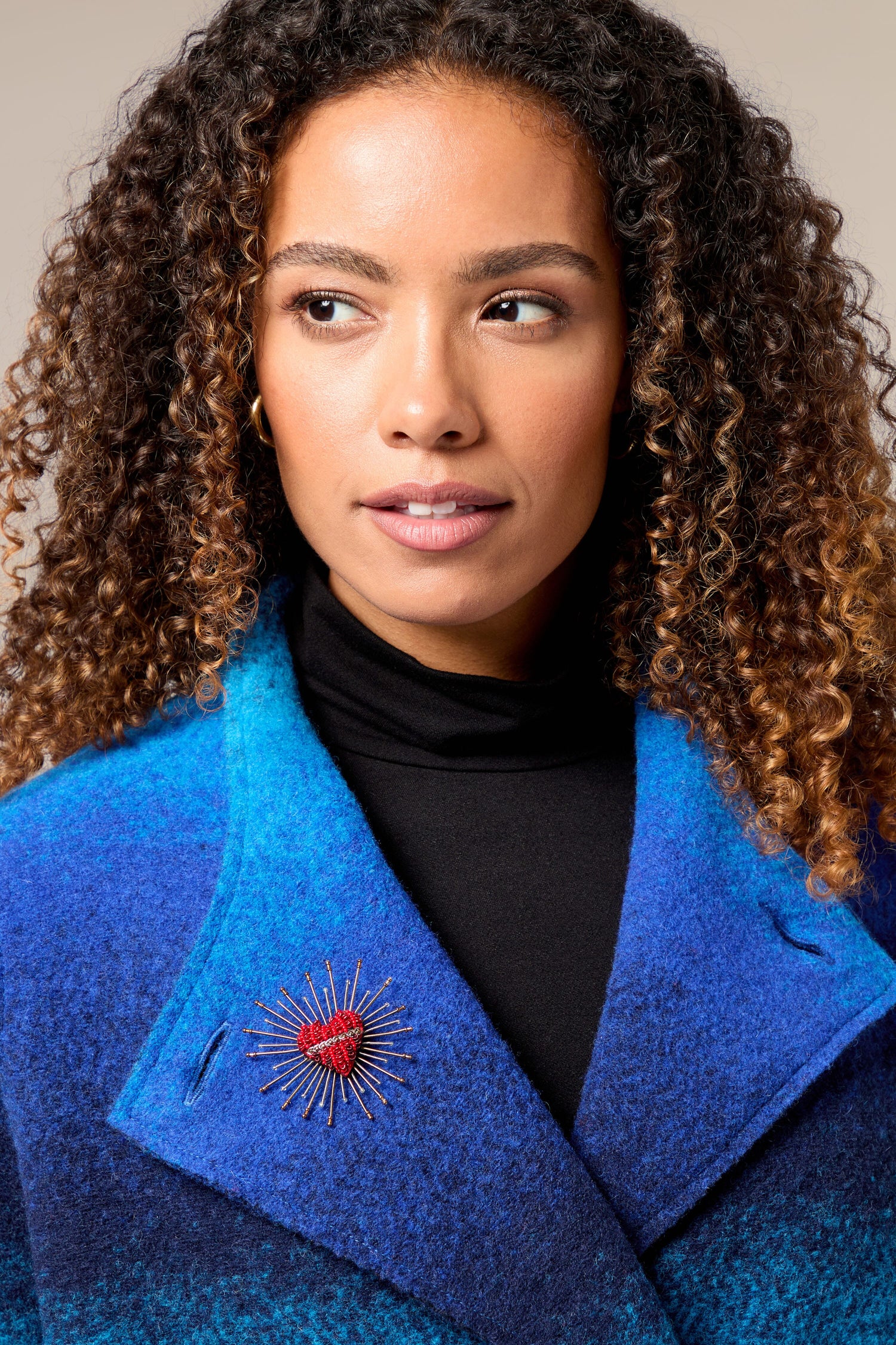 A woman wearing a blue coat with a Sacred Heart Embroidered Brooch.