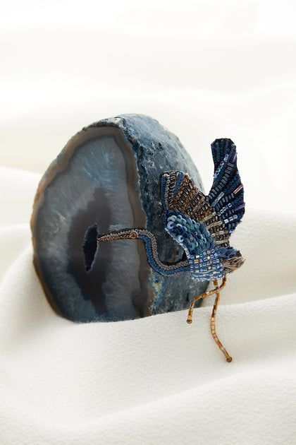 A stunning blue heron brooch is sitting on top of a piece of agate, creating a versatile accessory.