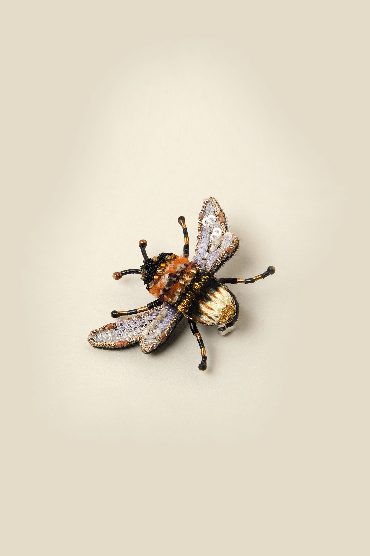 The Hand Beaded Humble Bee Brooch features intricate hand embroidery on a plain background, making it a sustainable and exquisite accessory.