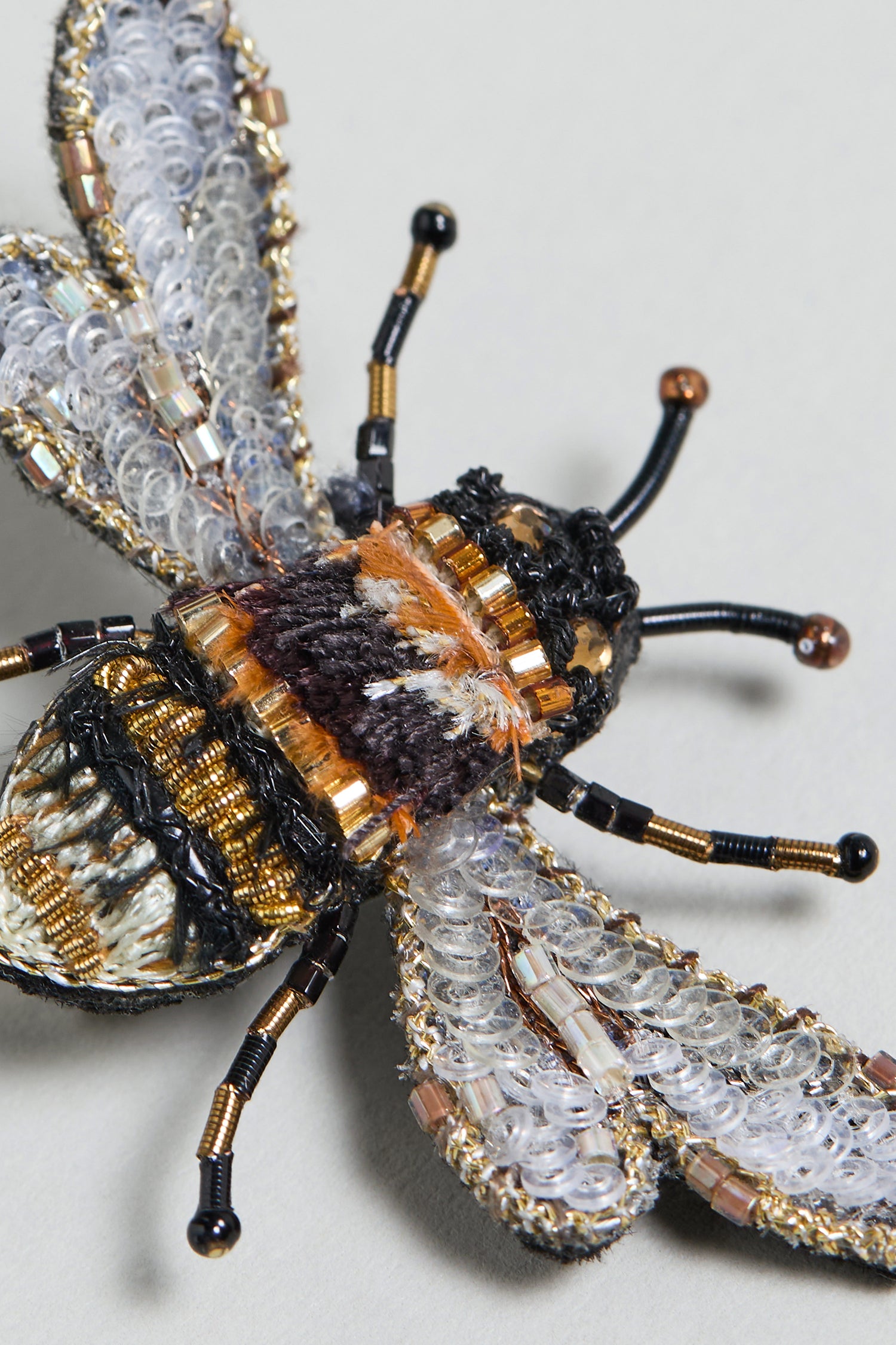 Close-up of a Hand Embroidered Humble Bee Brooch, crafted with black, gold, and silver threads plus metallic bead accents for striking detail—a stunning nature-inspired accessory on a light background.