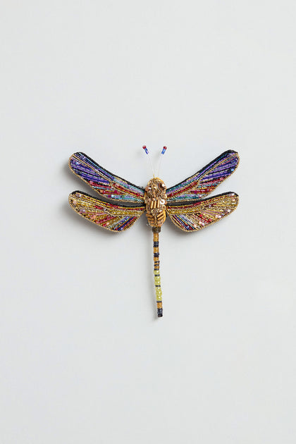 The Hand Beaded Hawker Dragonfly Brooch, featuring multicolored wings and a gold-toned body, is an exquisite piece of handmade jewelry displayed on a plain light background.