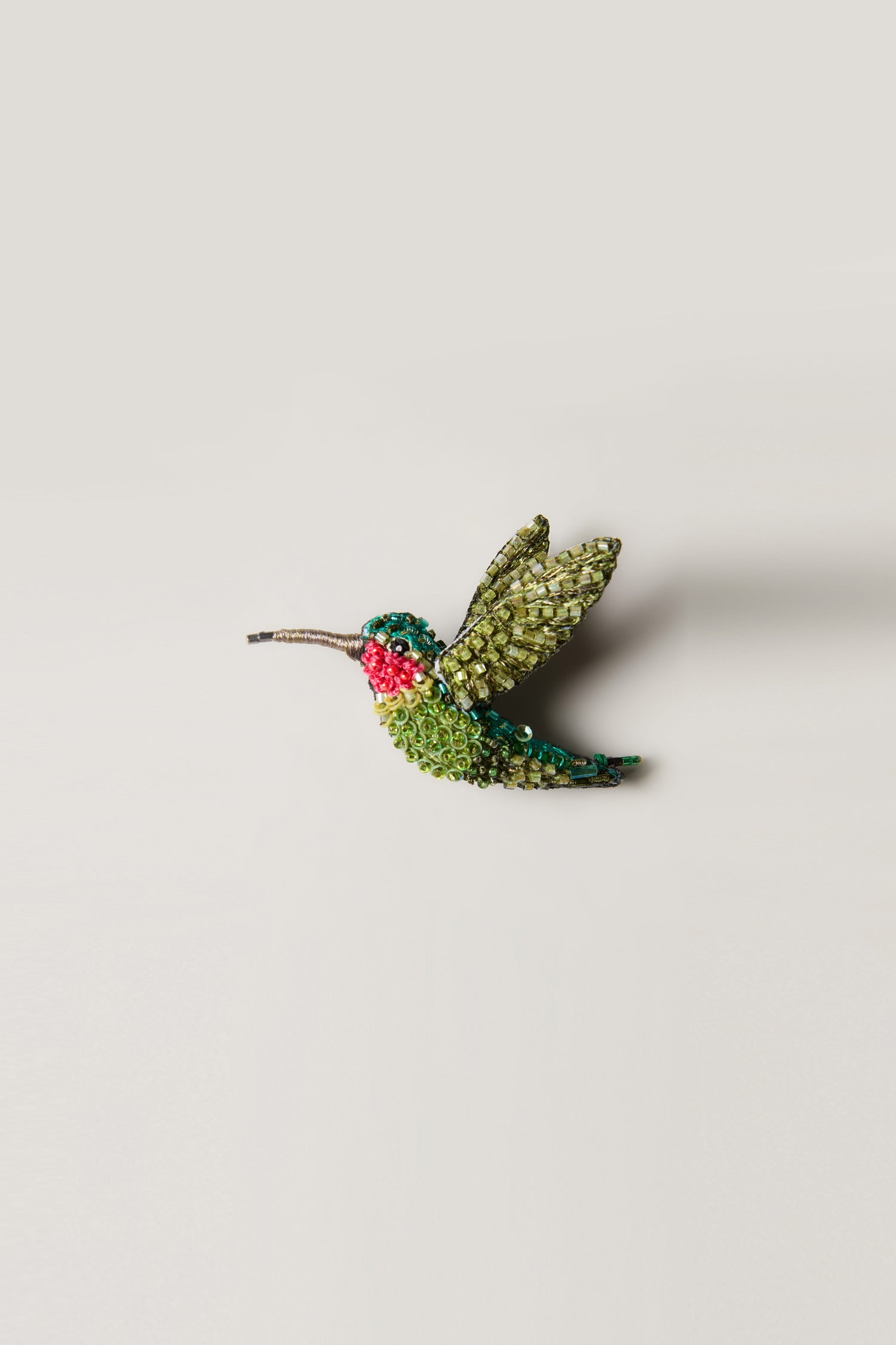 Hand Beaded Ruby Throated Hummingbird Brooch featuring handcrafted glass beads in green with red and white accents, displayed on a plain light background.