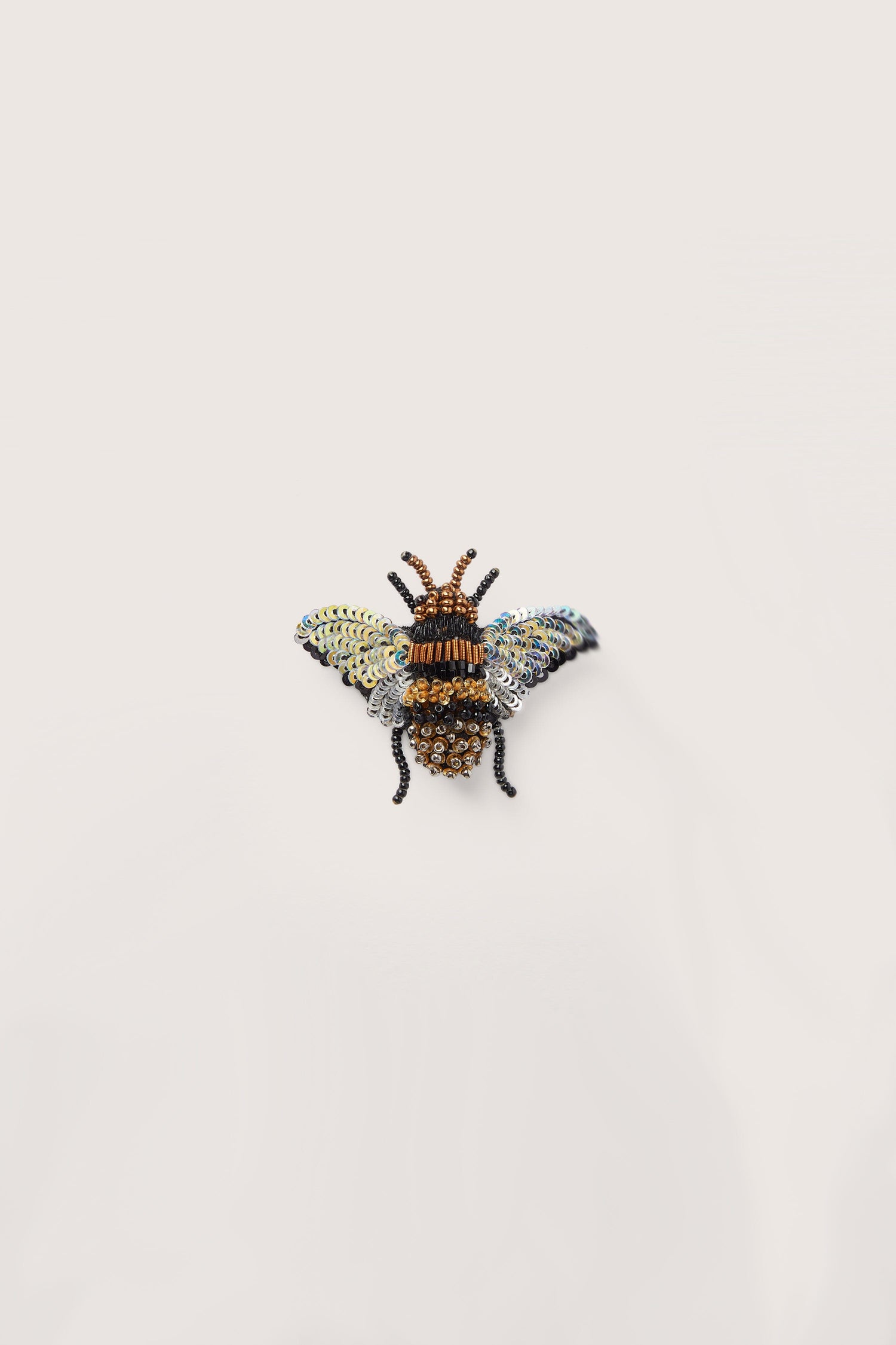 A versatile hand-embroidered holographic bee brooch on a white background.