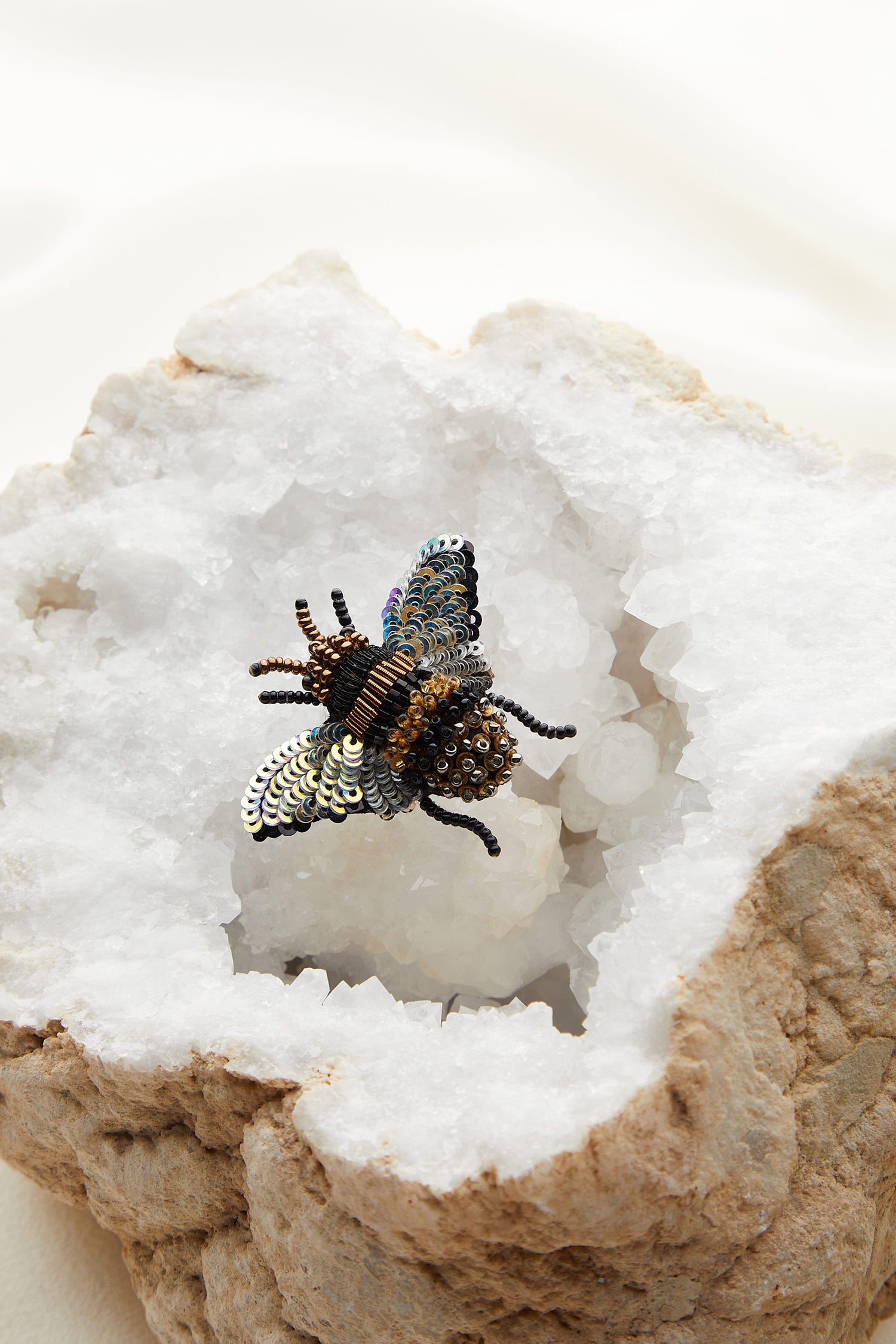 A versatile Hand Embroidered Holographic Bee Brooch featuring a bee hand-beaded on a rock.