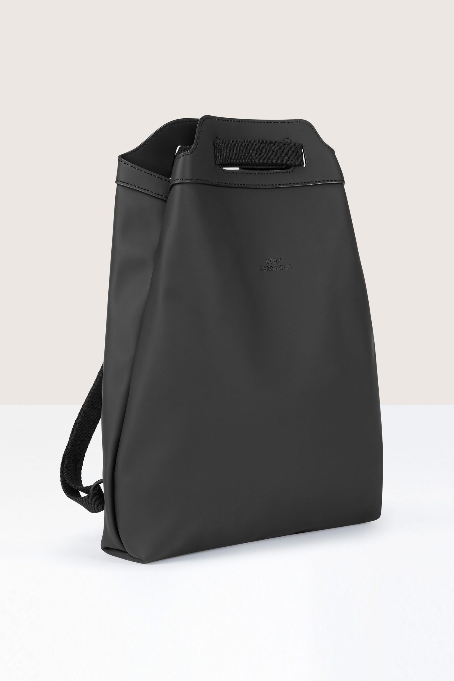 A black, rectangular, minimalist Una Backpack with a top handle and subtle logo on the front, crafted from recycled PET bottles, set against a plain background.