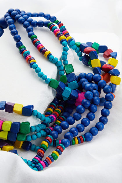 Wooden Twist Bead Necklace with various shapes including saturated wooden round beads displayed on a white fabric background.