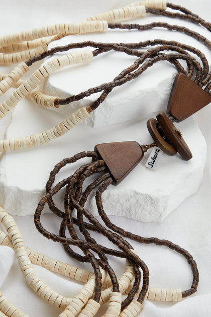 Coconut Cascade necklaces with large pendants displayed on a natural organic materials textured fabric.