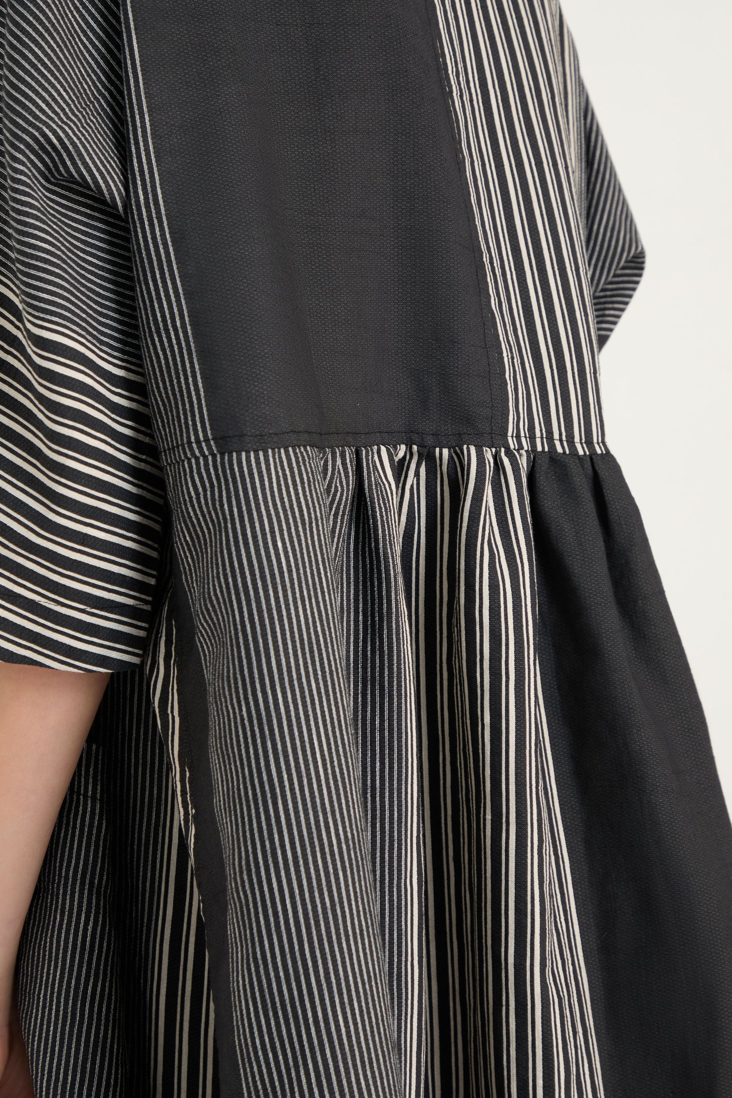 Close-up of a person wearing the Mixed Stripe Easy Dress, featuring black and white patchwork with vertical and horizontal stripes, paired with dangling star-shaped earrings.