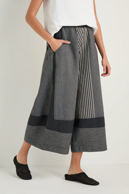 Person wearing Mixed Stripe Wide Leg Trousers with an elasticated waist and pockets, styled with a white sleeveless top and black flats, standing against a plain background.