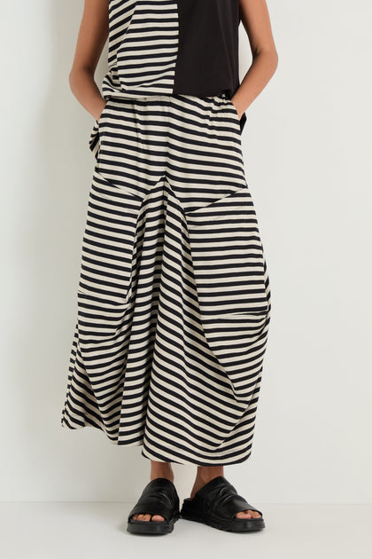 Model wears Stripe Balloon Trousers with a matching top and black sandals, standing against a plain white background for a chic, modern look.