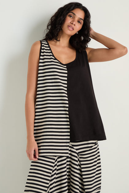 A woman wears the Stripe and Plain Sleeveless Top, paired with striped pants, as she stands against a plain white background.