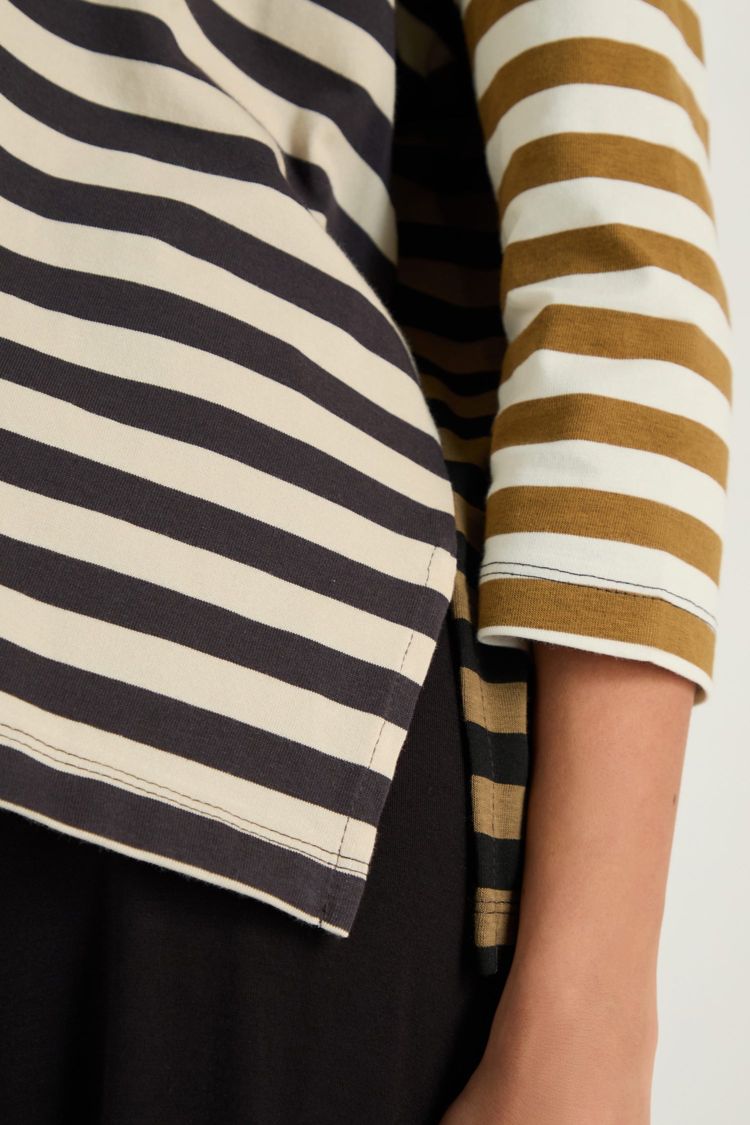 Close-up of a person wearing the Boxy Stripe Top in white, black, and mustard with black pants, featuring a relaxed silhouette.