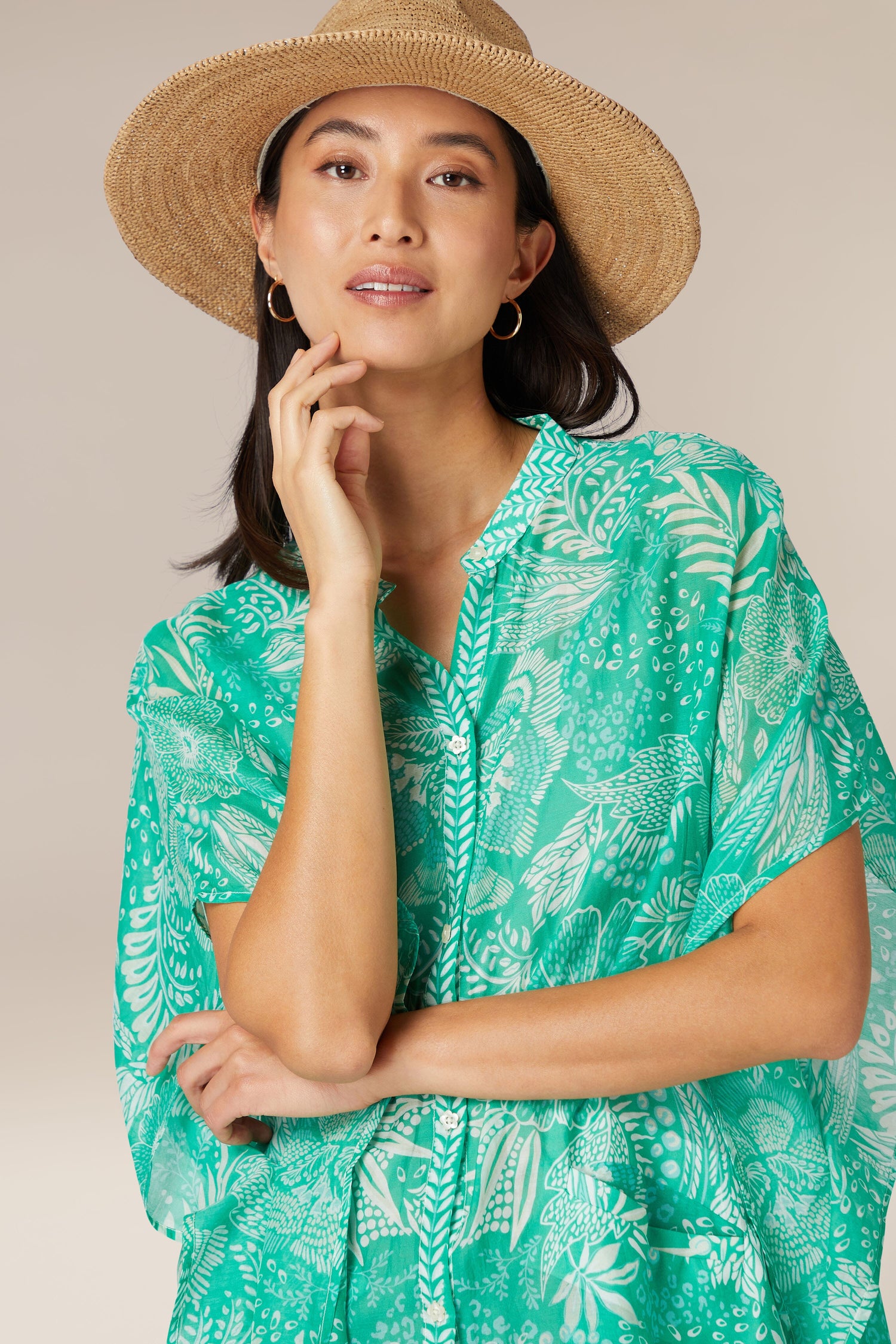 Woman in a Bohemian Button Bouquet Shirt Dress and straw hat posing thoughtfully.