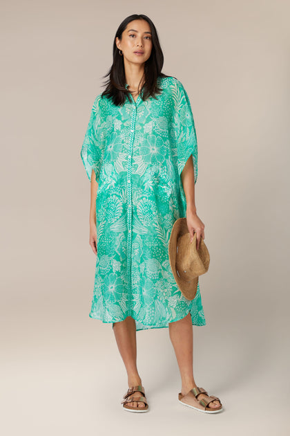 A woman in a Button Bouquet Shirt Dress holding a hat stands against a neutral background.