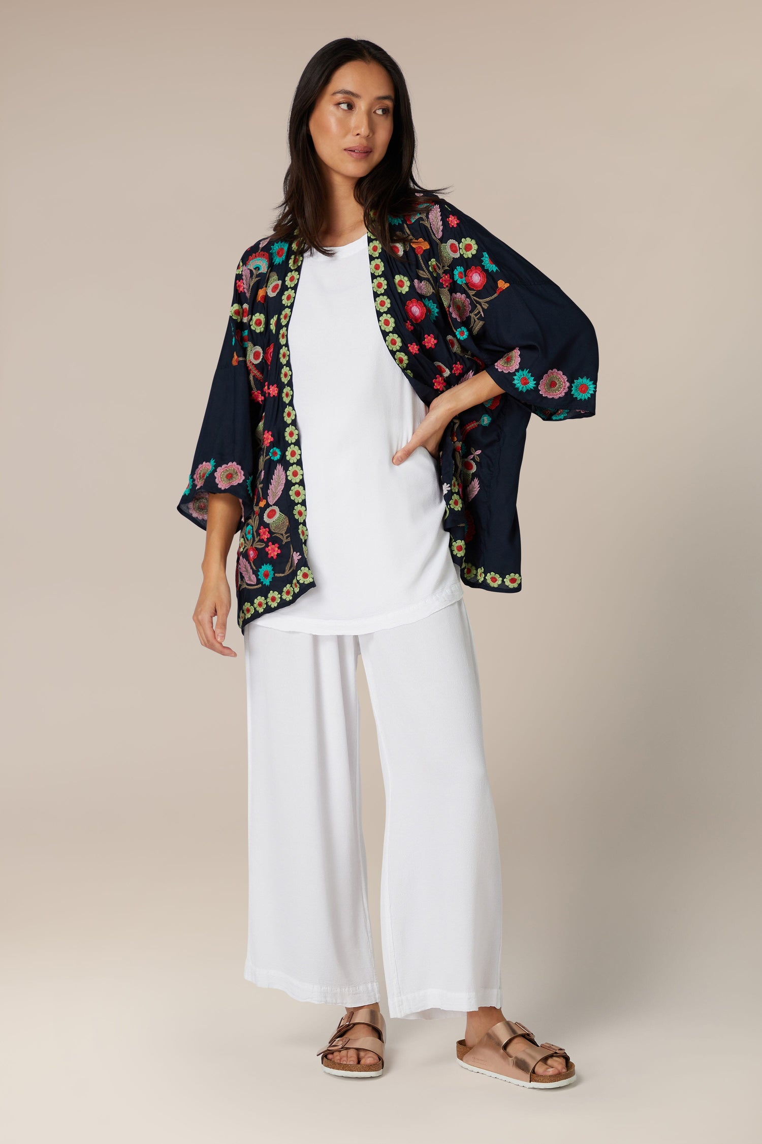 A woman modeling a white outfit with a lightweight, Embroidered Flower Garden Kimono.