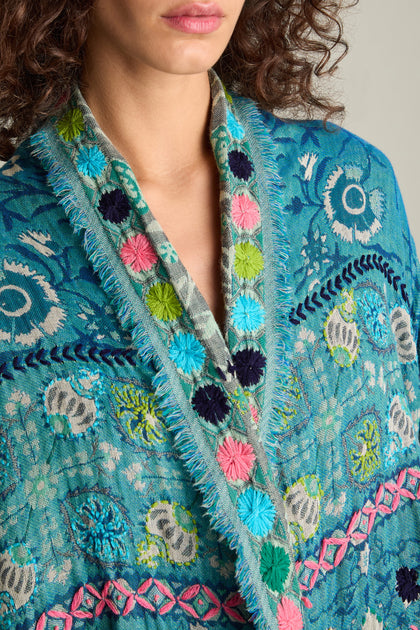 Close-up of a person wearing the Cerulean Hand Embroidered Jacket, featuring elaborate floral patterns and colorful designs along the edges.