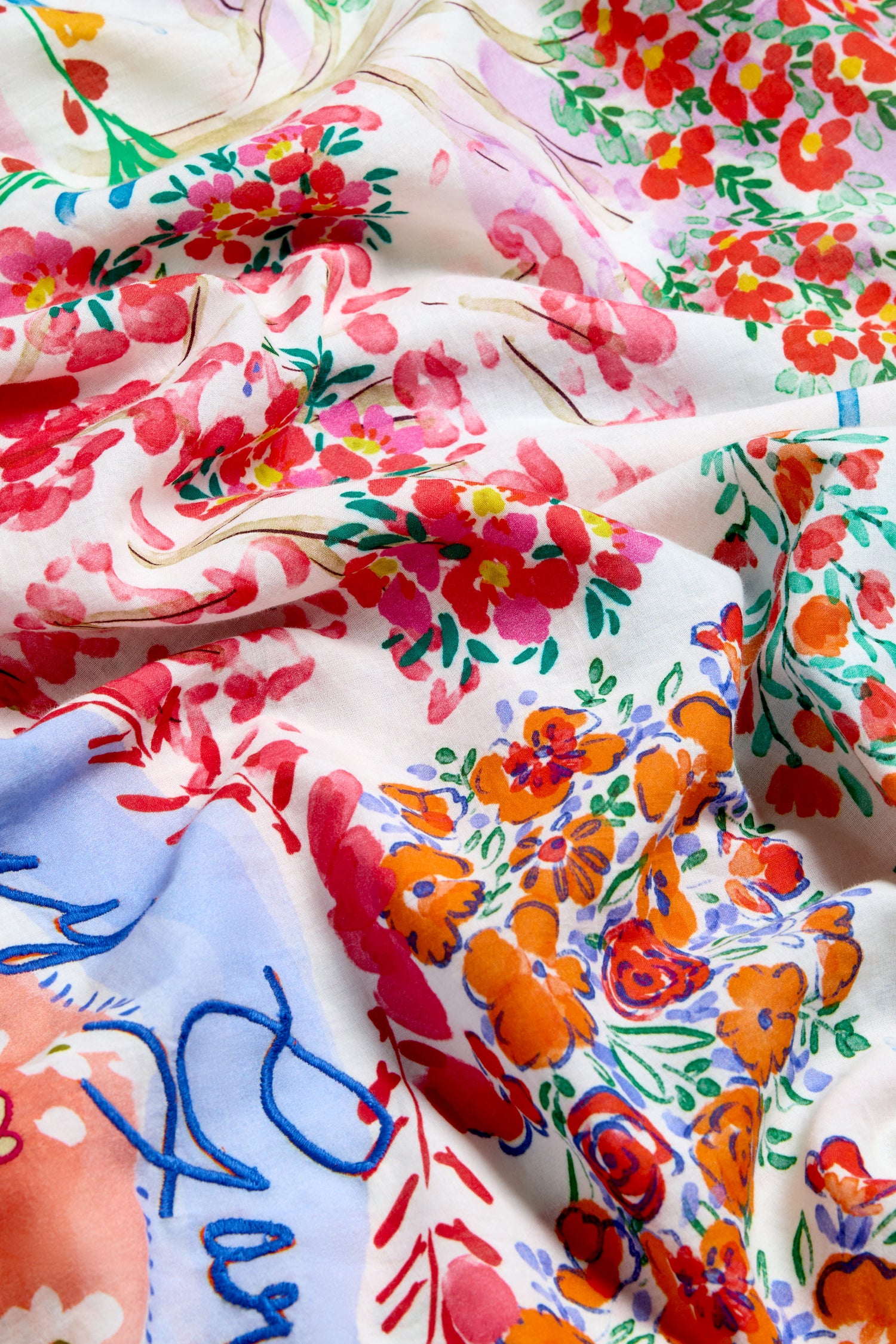 Close-up of the Floral Bouquet Cotton Scarf, showcasing its lightweight cotton fabric and vibrant floral print in red, orange, green, and blue on a white background, with emphasis on the texture and delicate folds.