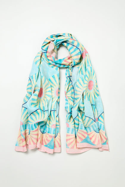 The Embroidered Parasols Cotton Scarf features light blue cotton with pink and white sunburst patterns, wavy lines, and subtle embroidery, shown on a plain white background.