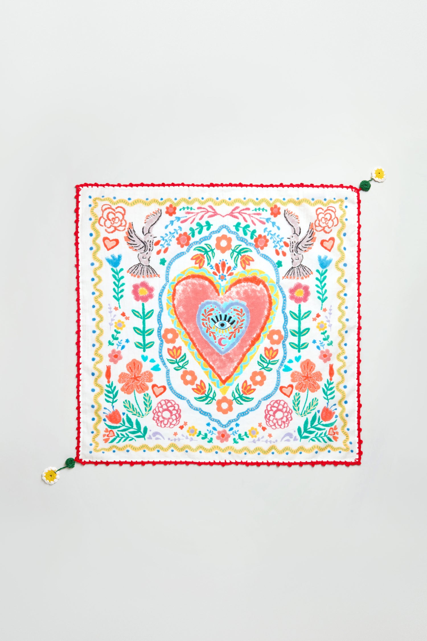 The Embroidered Love In Bloom Cotton Bandana features a central heart, vibrant floral and bird embroidery, scalloped edges, and flower-topped tassels at two corners.