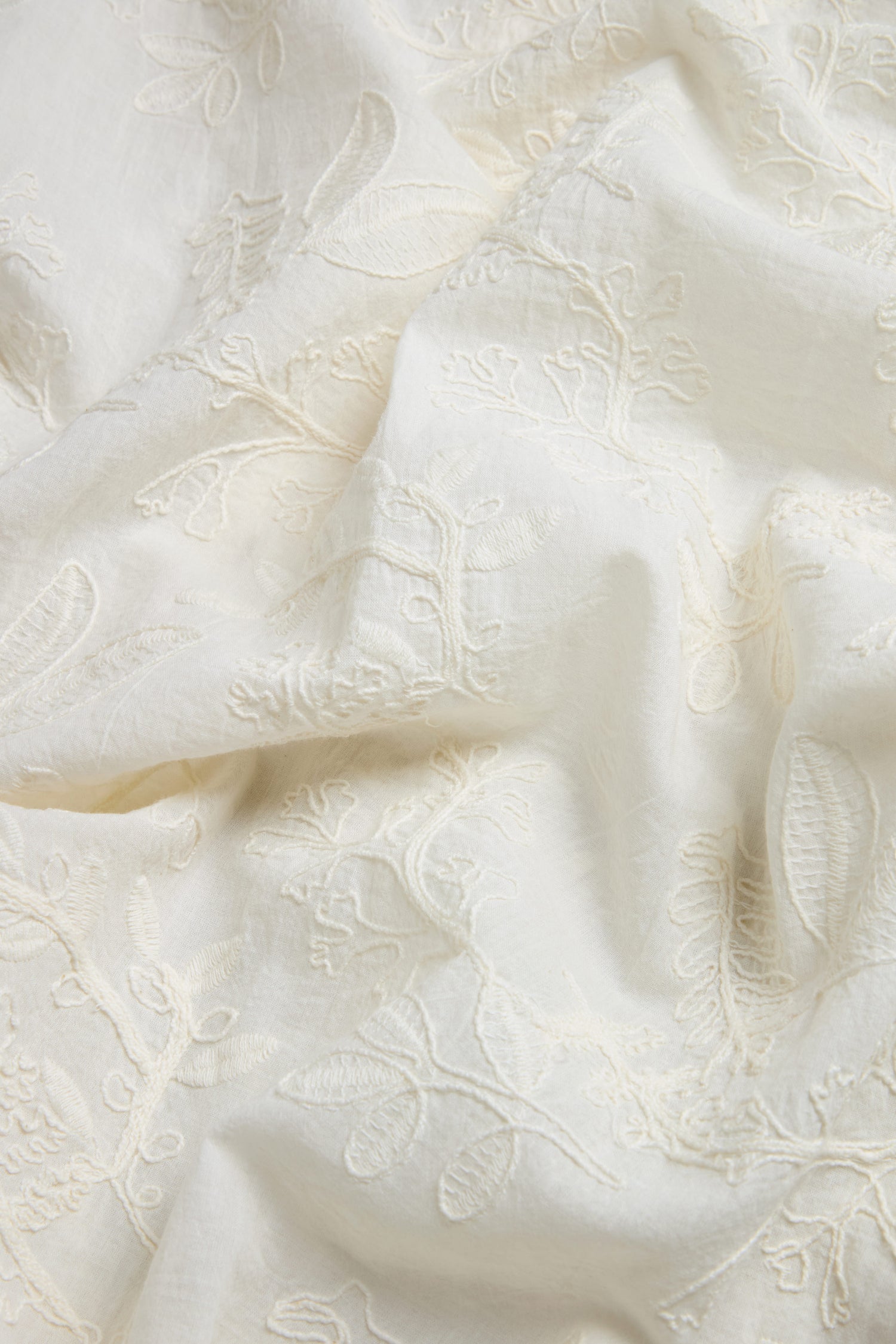 Close-up of the Embroidered Long Floral Shirt in off-white, featuring delicate floral embroidery and soft folds—ideal as a women’s lightweight shirt with subtle texture and charm.