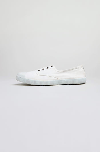 The Inglesa White Pumps, classic trainers made from recycled DREC cotton with a rubber sole and four eyelets, are shown in profile against a light gray background.