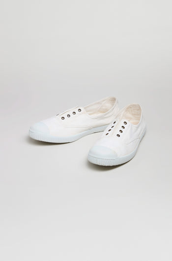 The Inglesa White Pumps are canvas trainers made with recycled DREC cotton, featuring white uppers, sturdy rubber soles, and metal eyelets, shown against a plain light background.
