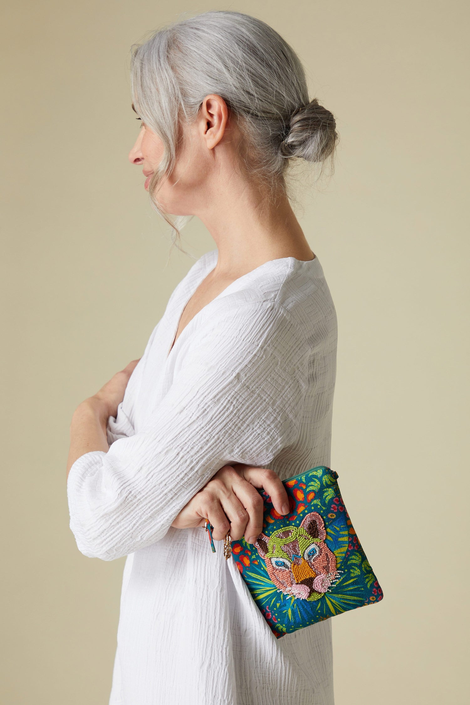 Woman with gray hair holding a Celeste Beaded Tiger Handbag with intricate embroidery.