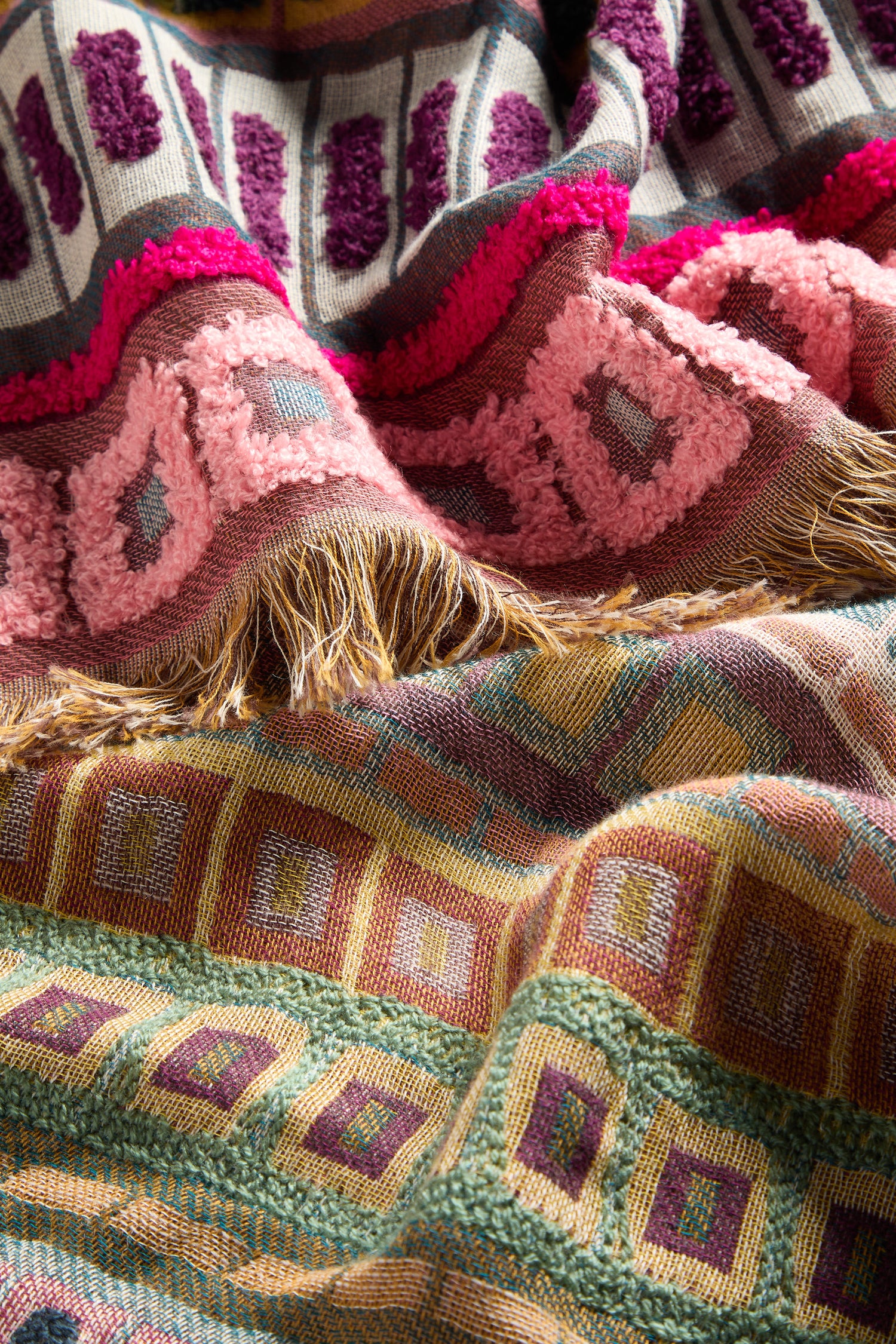 A close-up image showcases the Textured Cotton Scarf, adorned with intricate designs in shades of pink, green, yellow, and purple. The harmonious combination of woven and tufted textures accentuates its vibrant multicolored patterns, while 3D embroidered details elegantly capture the essence of seasonal transitions.