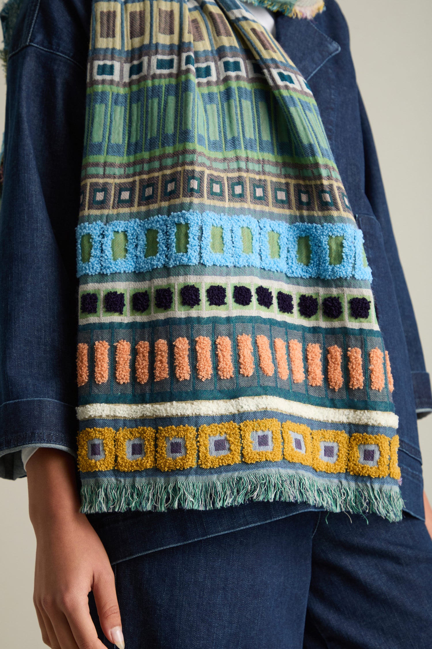 Close-up of a person wearing the Textured Cotton Scarf with geometric designs, transitioning between seasons, draped over a dark blue jacket.