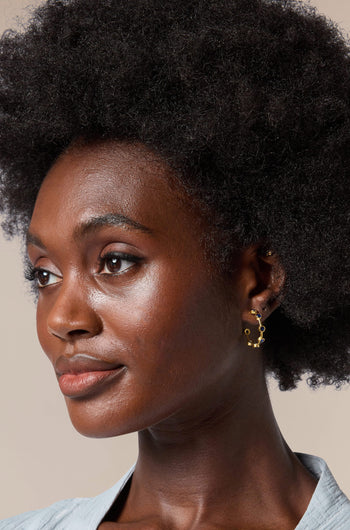 A woman with afro hair wearing Handcrafted Seven Stone Hoop Earrings handcrafted by Istanbul's skilled artisans.