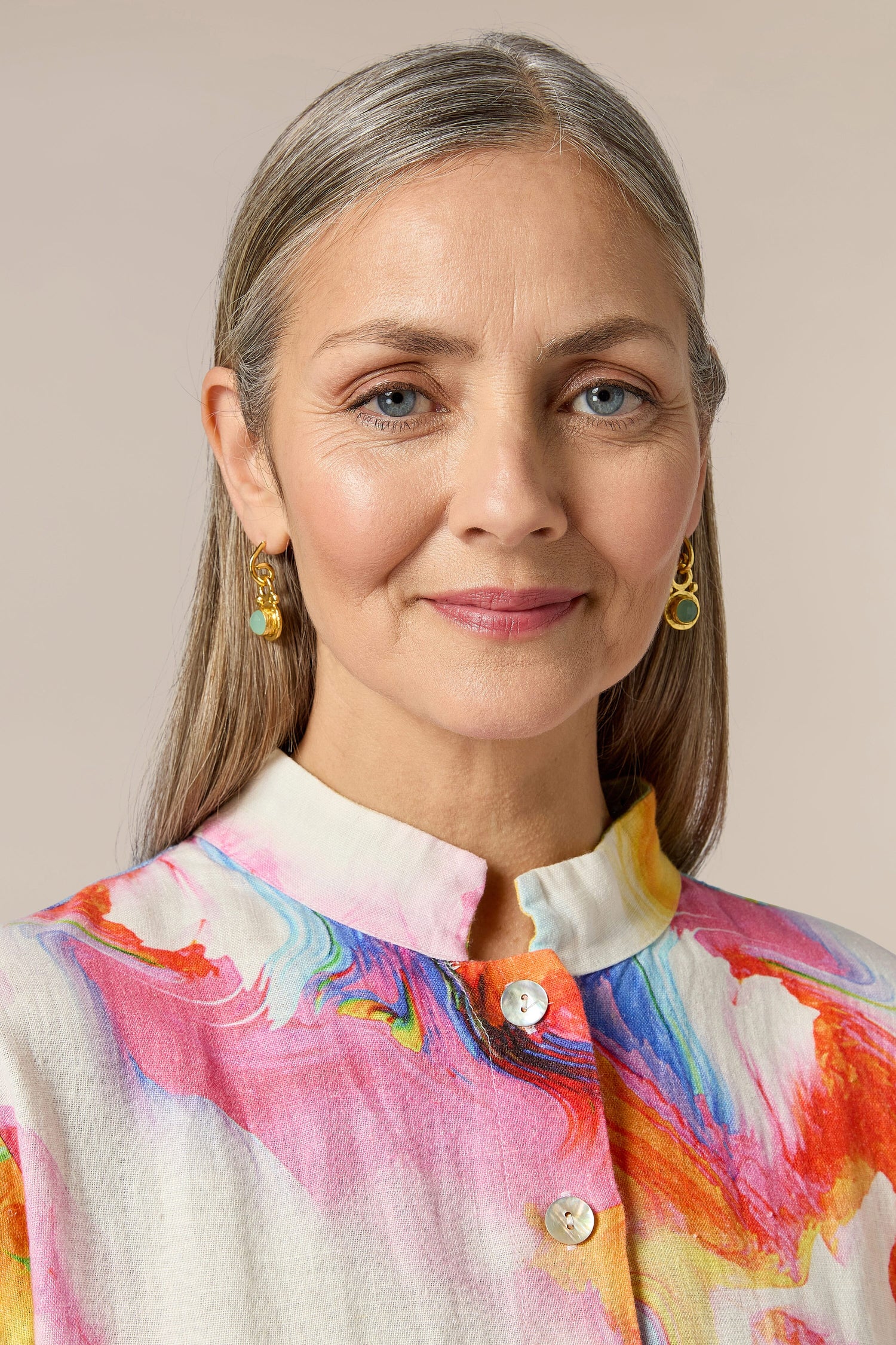 A woman wearing the Handcrafted Aquamarine Drop Earrings in Istanbul, elevating her colorful shirt and overall appearance with their stunning design.