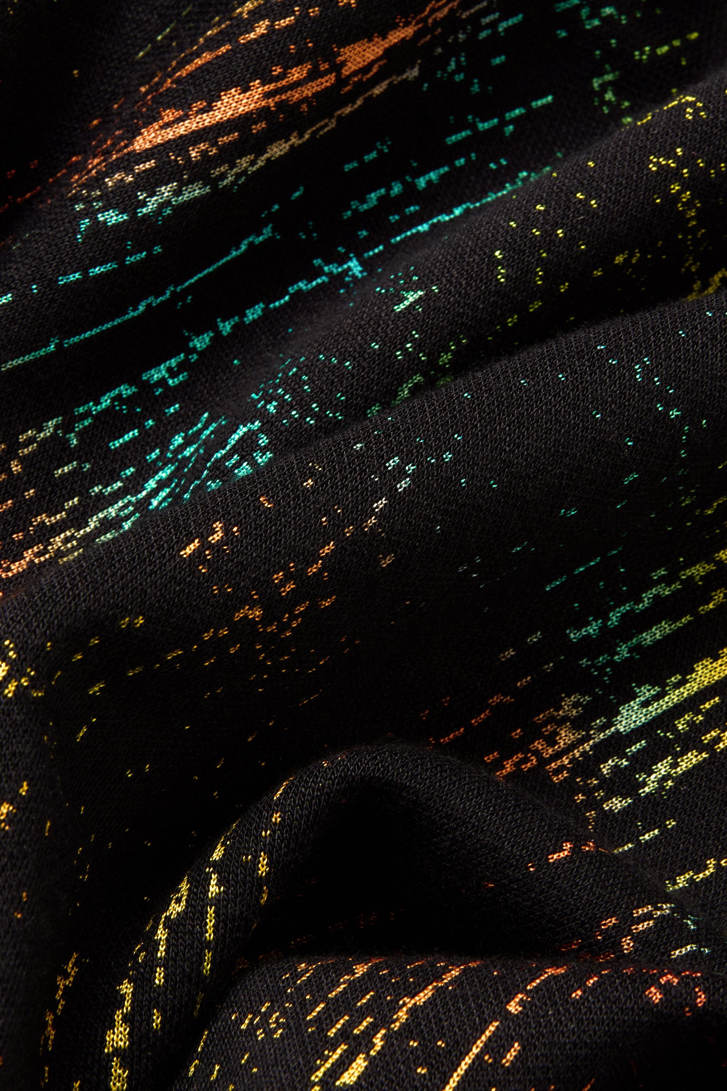 Close-up of the Space Dye Jacquard Jersey Dress in black, featuring orange, yellow, green, and blue streaks and textured folds.