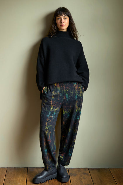 A person wearing a black mock-neck sweater and Space Dye Jacquard Bubble Trousers, paired with black lug-sole boots.
