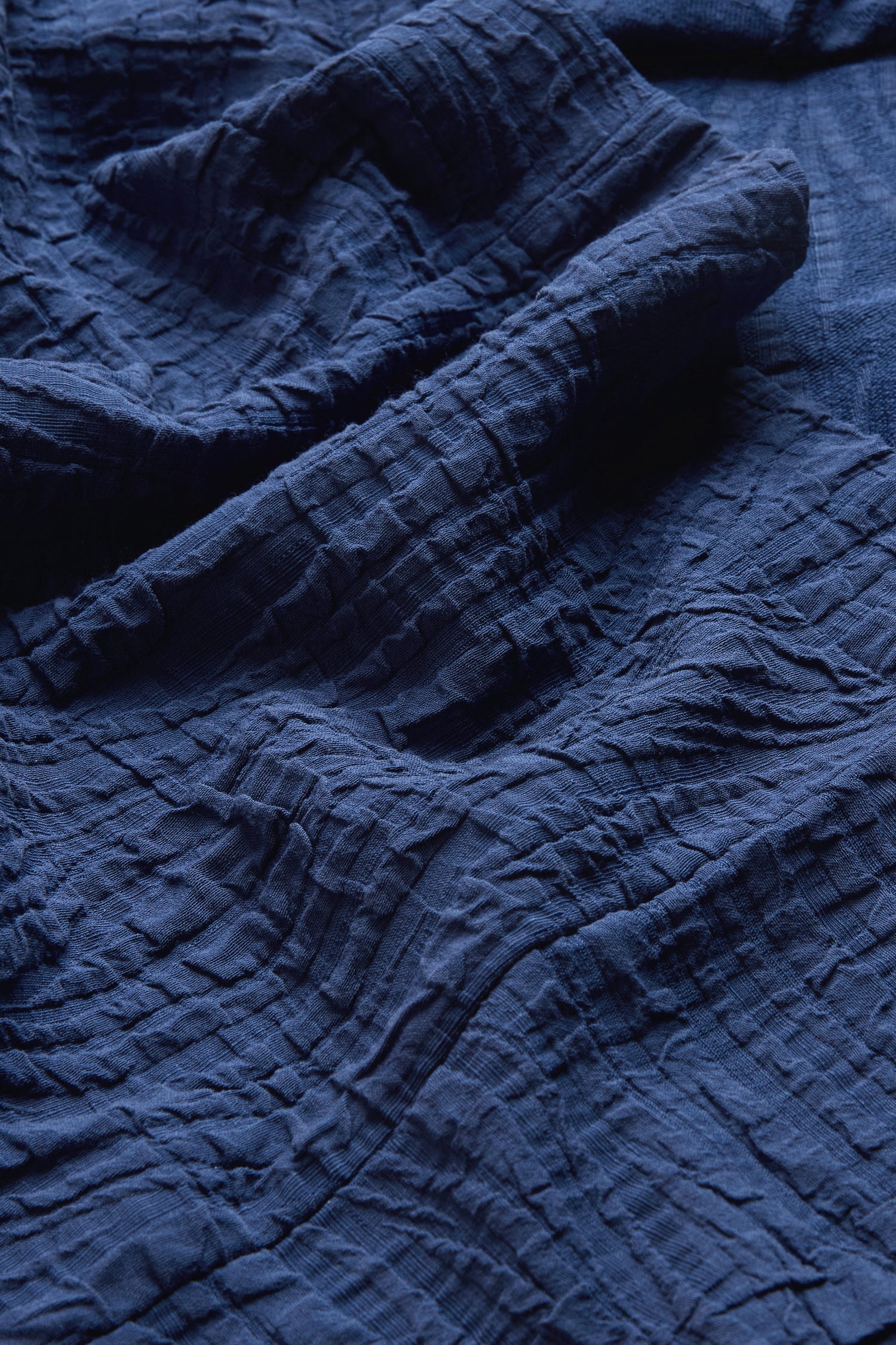Close-up of cobalt blue, crinkled fabric with a wave-textured surface and visible folds, characteristic of the Cobalt Wave Textured Crinkle Cowl Neck Top—perfect for a relaxed, boxy silhouette.