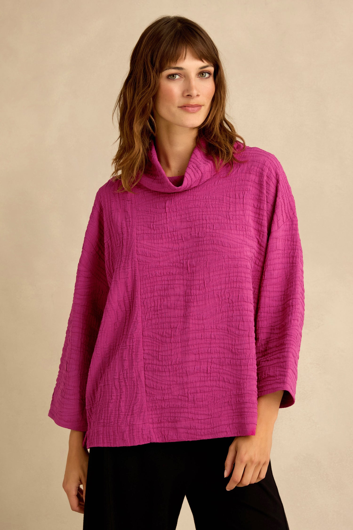 A woman wearing the Magenta Wave Textured Crinkle Cowl Neck Top, featuring a wave crinkle fabric, three-quarter sleeves, and a relaxed boxy silhouette, stands against a plain beige background.