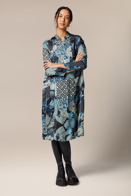 A woman wearing a Symphony Shirt Dress in an ethereal blue floral print A-line dress.