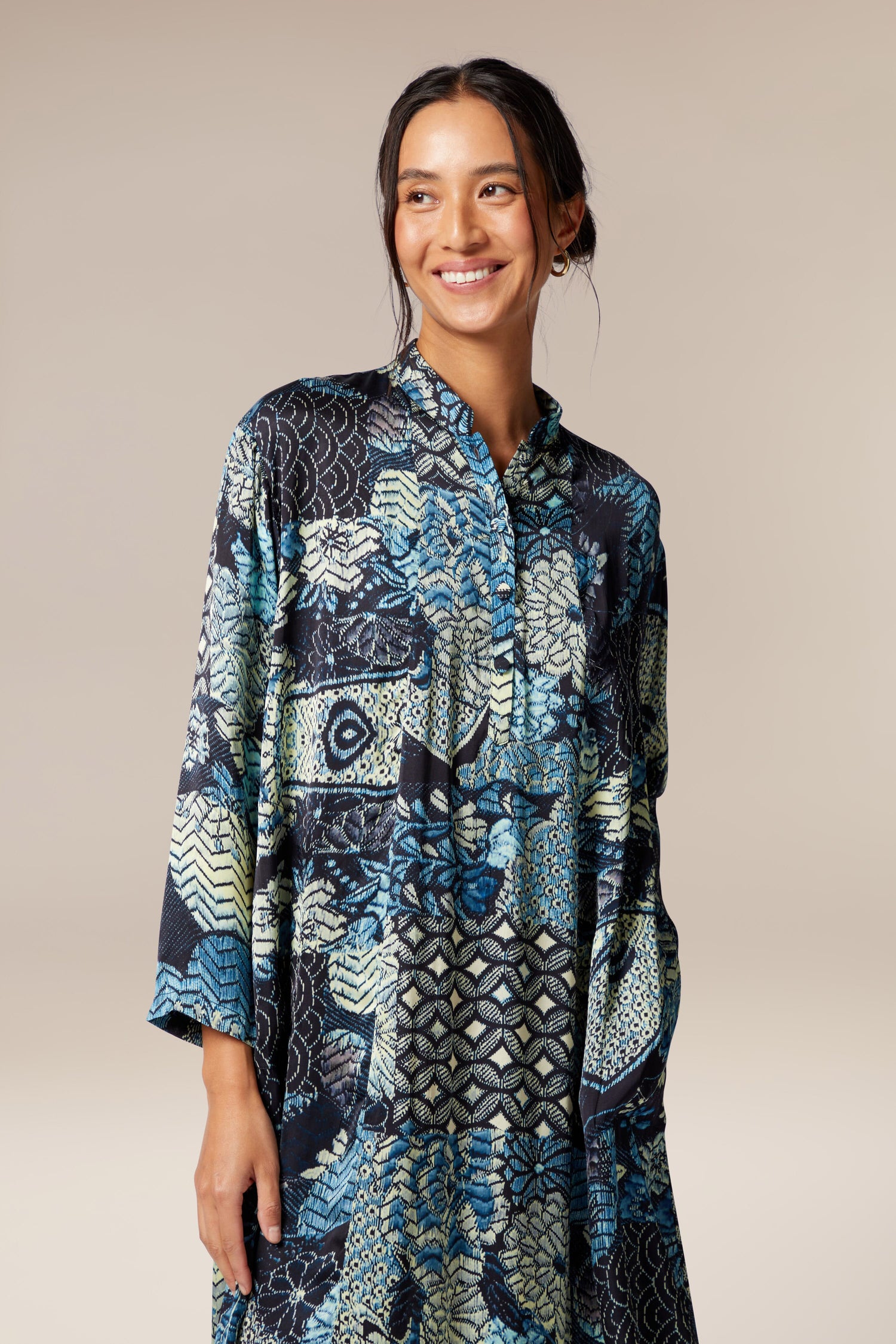 A woman wearing the Symphony Shirt Dress, an ethereal blue and black paisley print dress.