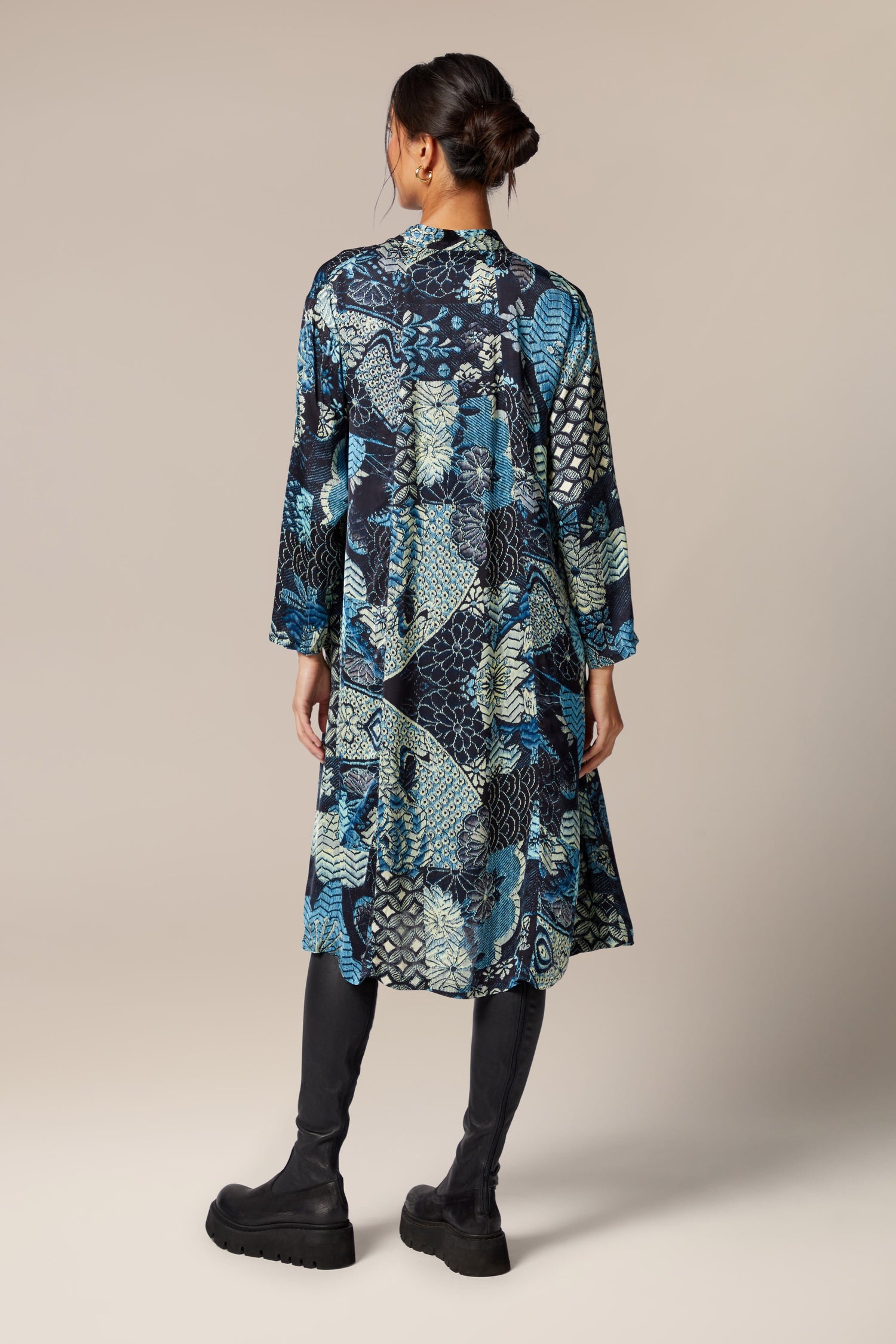 The back view of a woman wearing a Symphony Shirt Dress, an ethereal blue and black camouflage print dress.