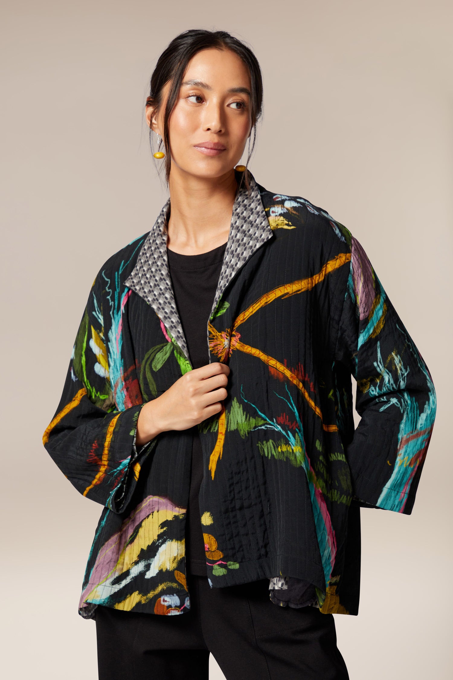 A woman wearing a Painterly Floral Jacket with a large-scale multi-colored print.