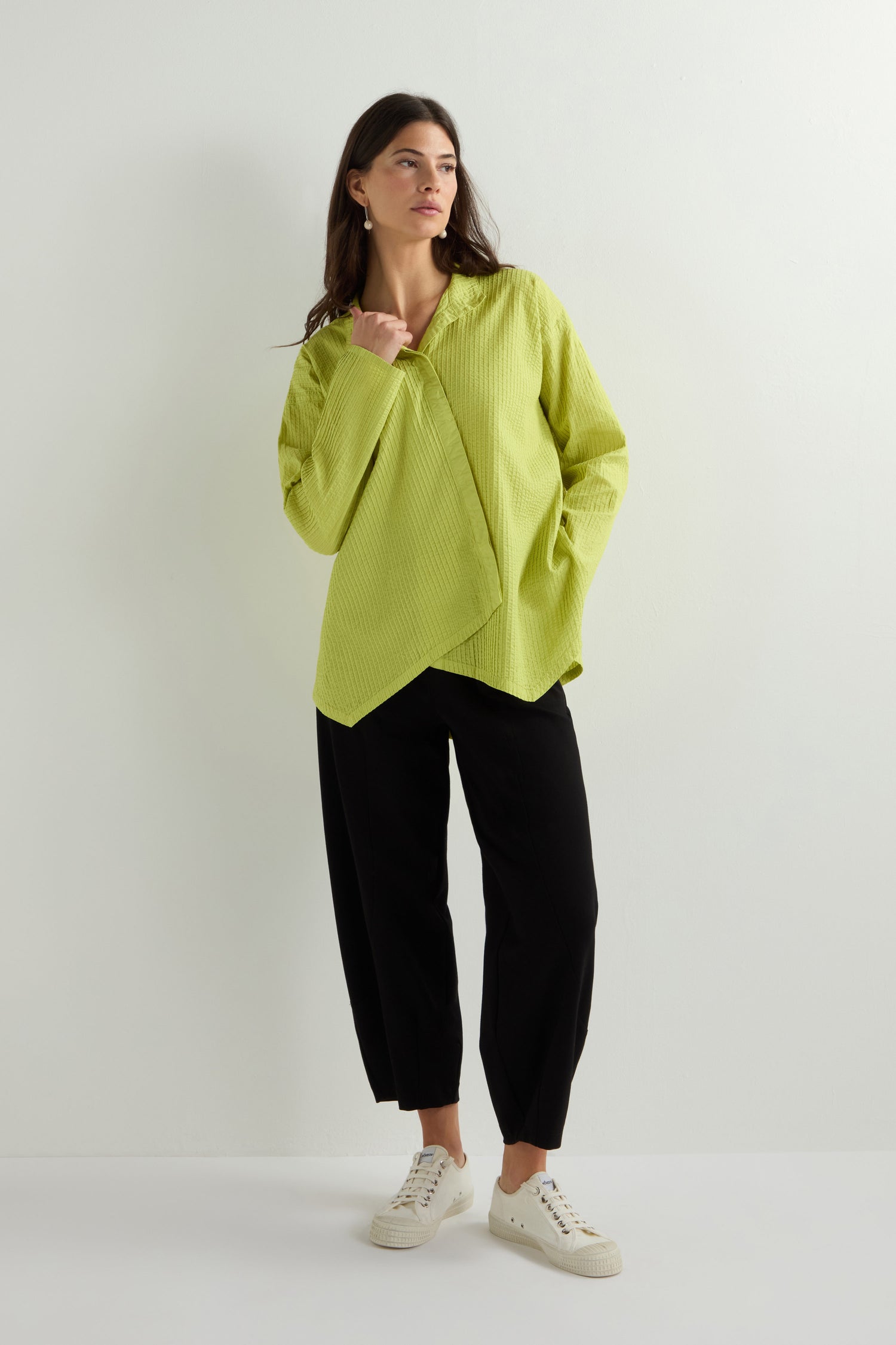 A person in a lime green Asymmetric Cotton Pleated Shirt by Yacco Maricard and black pants stands against a plain background.