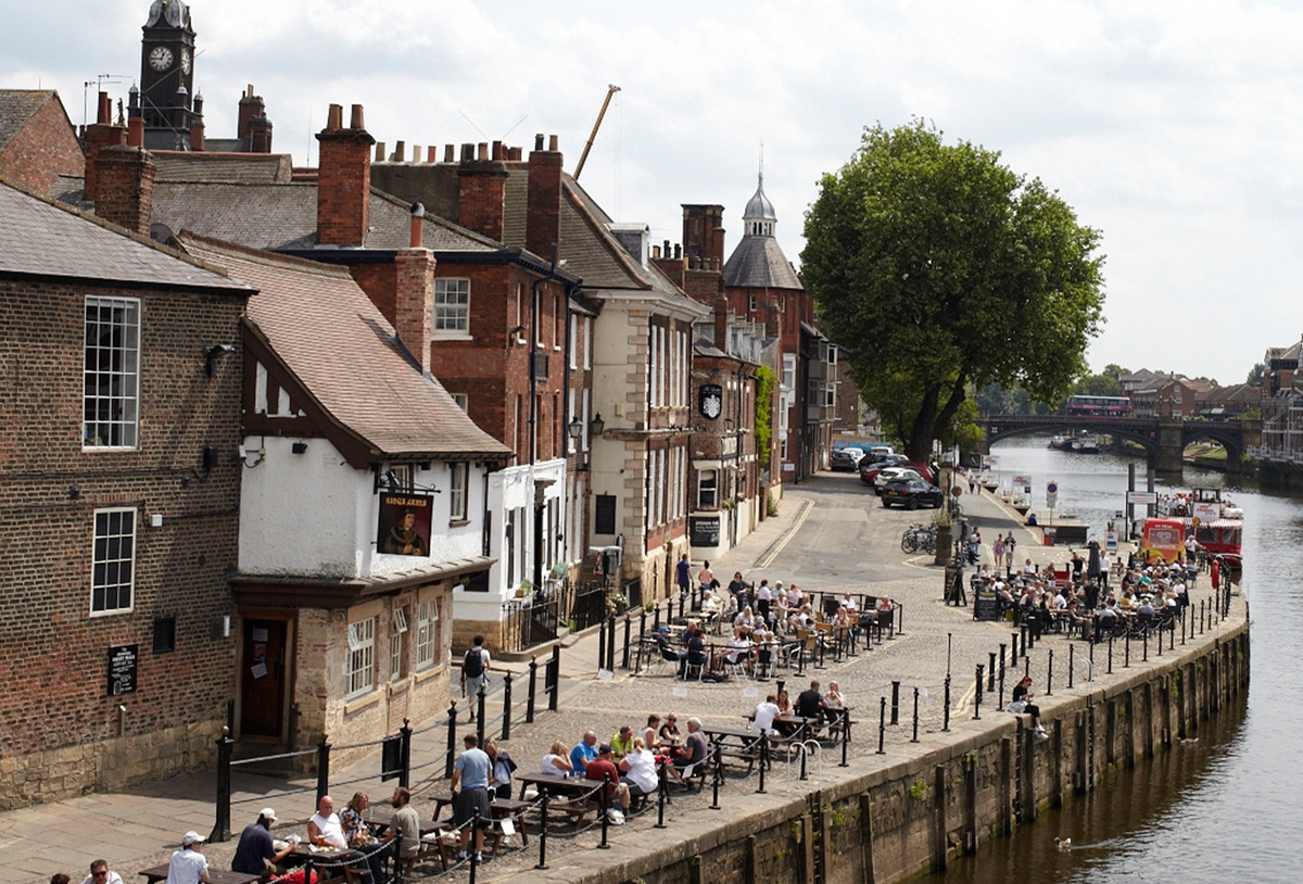 people sat outside pubs next to the river in york